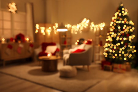 Blurred view of living room with armchairs, Christmas tree and glowing lights at nightの写真素材