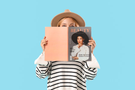 Beautiful mature woman with magazine on blue backgroundの写真素材
