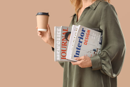 Beautiful mature woman with magazines and cup of coffee on beige background, closeupの写真素材