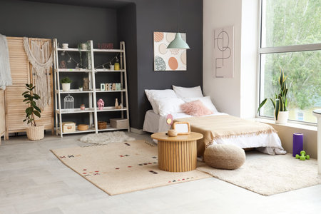 Interior of teenager's room with bed, table and shelf unit