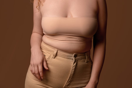 Beautiful young body positive woman in stylish jeans on brown background, closeupの写真素材