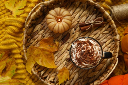 Autumn composition with cup of cocoa, leaves, candle and wicker tray on plaid as backgroundの写真素材