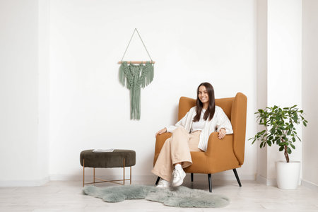 Young woman sitting in armchair in living room