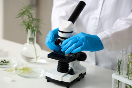 Female scientist working with microscope and plants samples in laboratory, closeup