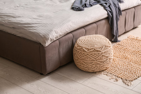 Stylish modern bed with fresh clean bedding and wicker ottoman in room at home, closeupの写真素材