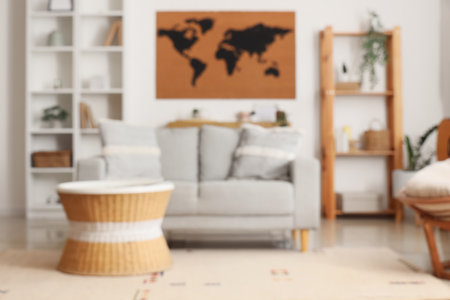 Blurred view of living room with sofa, table and world map on white wallの写真素材