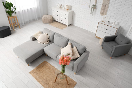 Interior of living room with sofa and gladiolus flowers in vase on table