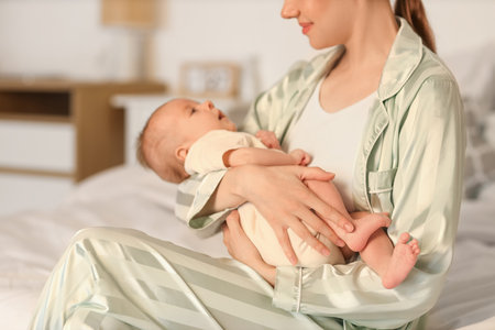 Mother with her little baby sitting in bedroom at night, closeupの写真素材