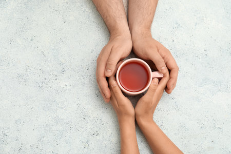 Loving young couple with cup of tea holding hands on grunge white backgroundの写真素材