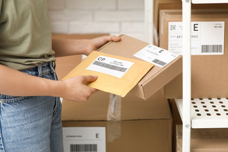 Woman with parcels at postal warehouse, closeup