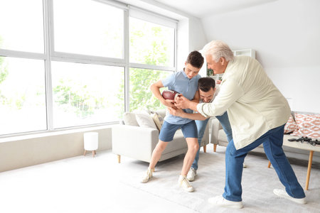 Teenage boy with his dad and grandfather playing rugby at homeの写真素材