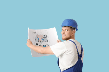 Male contractor with house plan on blue backgroundの写真素材