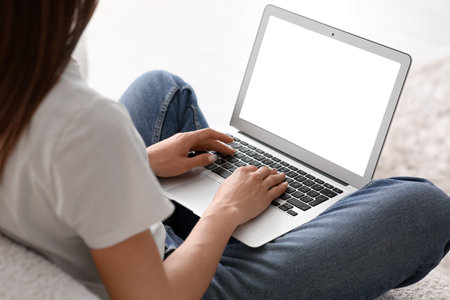 Young woman sitting on sofa and using laptop in living room, closeupの写真素材