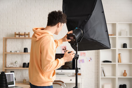 Professional male photographer with modern camera and softbox working in studioの写真素材