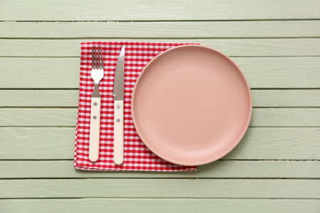 Table setting with plate, cutlery and napkin on green wooden backgroundの写真素材