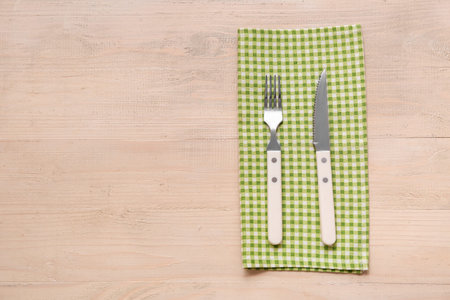 Napkin and stylish cutlery on wooden background