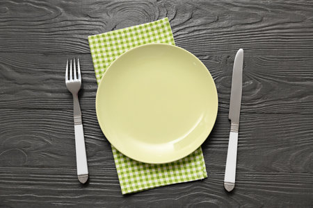Table setting with plate, cutlery and napkin on brown wooden backgroundの写真素材