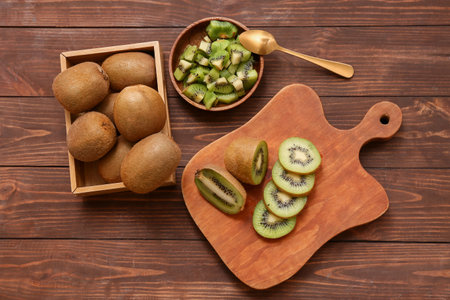 Board and bowl with cut fresh kiwi on wooden backgroundの写真素材