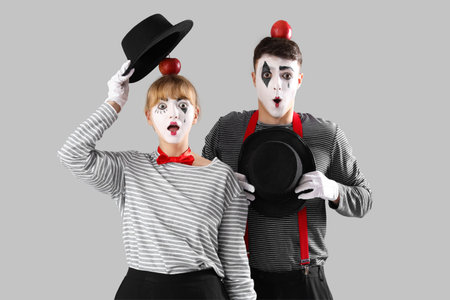 Couple of pantomimists with apples on gray backgroundの写真素材