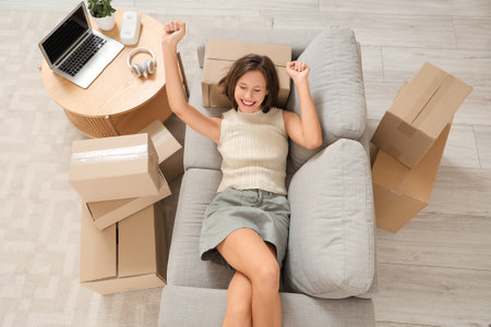 Young happy woman with laptop and many parcels lying on sofa at home, top viewの写真素材