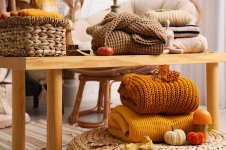 Stacks of stylish clothes with autumn decorations on wicker ottoman in dressing roomの写真素材
