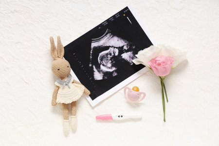 Composition with baby toy, sonogram image, pregnancy test and nipple on grunge white background