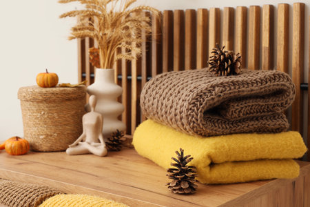 Stack of stylish clothes with autumn decorations on commode in living room, closeupの写真素材