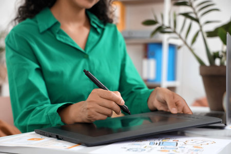 Female web designer drawing with graphic tablet at table in office, closeup