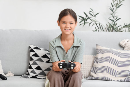 Little girl playing video game on sofa at home