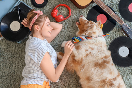 Young woman with Australian Shepherd dog and vinyl disks for record player lying on carpet, top viewの写真素材