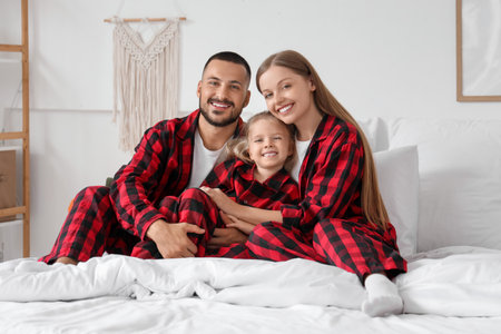 Happy parents with their little daughter sitting in bedroomの写真素材