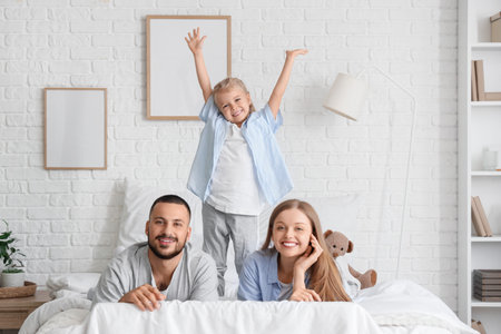 Happy little girl with her parents in bedroomの写真素材