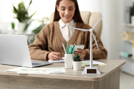 Wind turbine model on table of female engineer in office, closeup