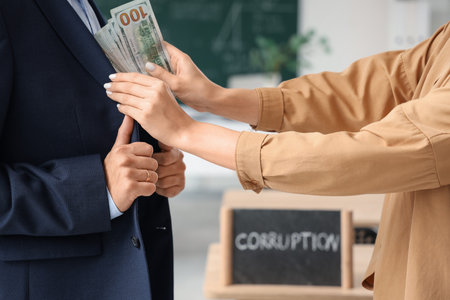 Male teacher taking bribe in classroom, closeup. Corruption conceptの写真素材