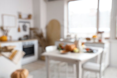 Blurred view of light kitchen with autumn decor, counters and dining tableの写真素材