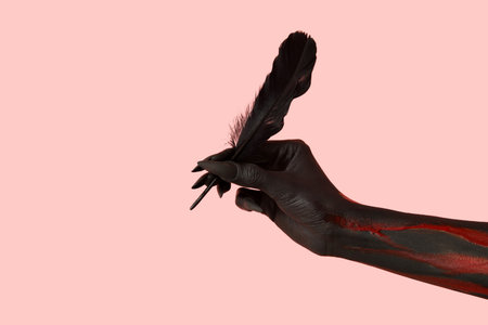 Black witch hand with claws and feather on pink background. Halloween celebrationの写真素材