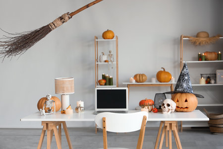 Workplace with laptop, Halloween pumpkins and burning candles in officeの写真素材