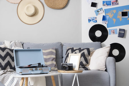 Interior of stylish living room with gray sofa, record player and mood board