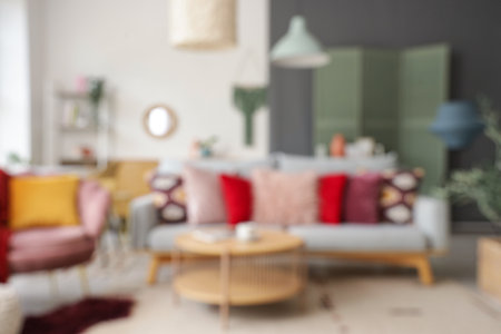 Blurred view of stylish living room with armchair, table and cushions on sofaの写真素材