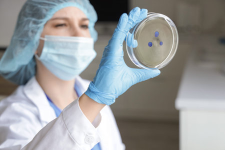 Female scientist with Petri dish in laboratory, closeup
