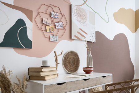 Stylish artist's workspace with books and mood board hanging on wall