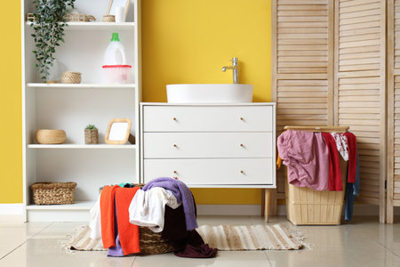 Stylish bathroom with sink, laundry baskets and folding screenの写真素材