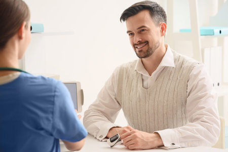 Young man with pulse oximeter visiting doctor in clinic
