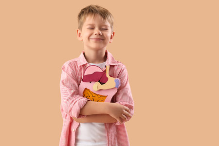 Little boy with paper digestive system on beige background