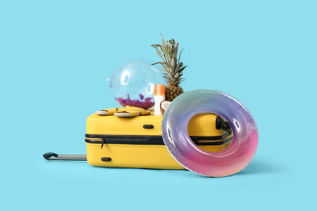 Inflatable ring, suitcase and beach accessories on blue background. Travel conceptの写真素材