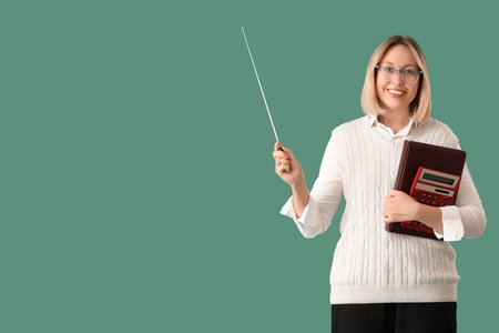 Mature female math teacher with pointer, calculator and folder on green backgroundの写真素材