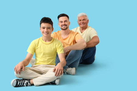 Teenage boy with his dad and grandfather sitting on blue background