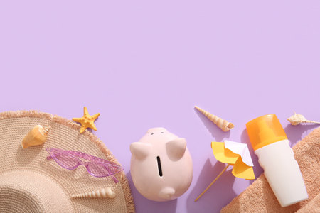 Piggy bank, sunscreen, starfish, seashells, sunglasses, hat, decorative umbrella and towel on lilac backgroundの写真素材