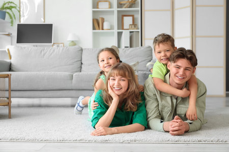 Happy parents with their little children lying on floor at home