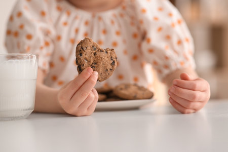 Cute little girl with cookies and milk at homeの写真素材